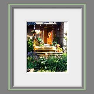 A photo of an inviting front porch next to a perennial garden full of summer flowers and a golden retriever dog basking in the warm light.