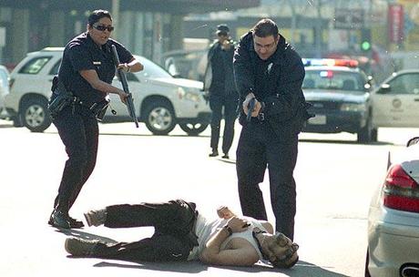 LAPD officers run with guns drawn to the suspected gunman after the shooting spree on Vine Street in Hollywood