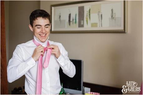 Groom preparation photography East Riddlesden Hall Wedding Photographer groomsman putting on pink tie