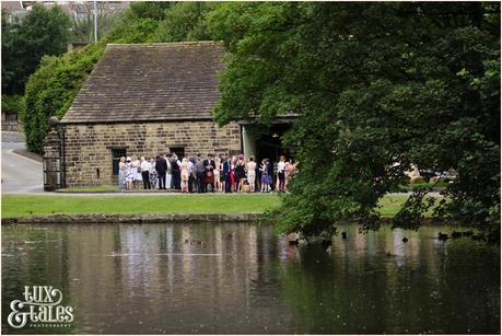 East Riddlesden Hall Wedding Photography pink English garden theme | Guests outside of barn across lake