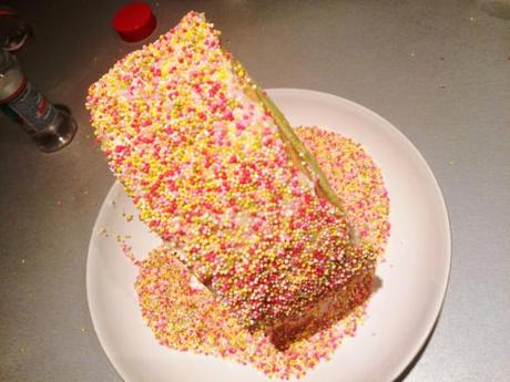 Sprinkles & Checkerboard Birthday Cake covering cake in sprinkles rolling sides in hundreds and thousands