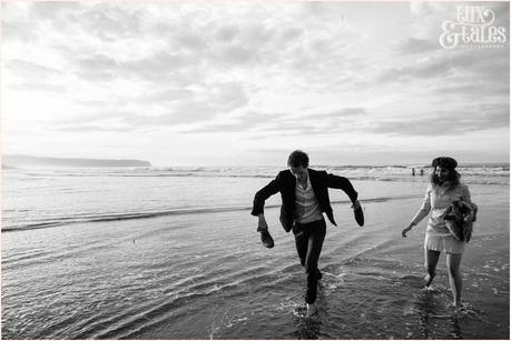 Whitby Love Shoot | Cass & Josh Photography Engagement Shoot in Whitby | Girl wearing Red Flower crown | Alterntive Couple whereing Vintage clothing | Running in the ocean man holding shoes