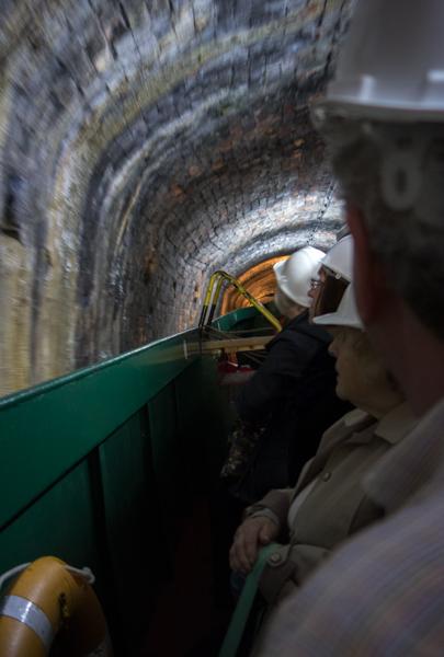 Tunnel with boat and tourists in hard hats