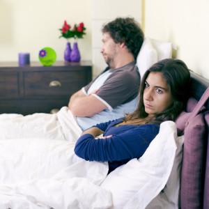 Unhappy couple in bed after fight not talking retro style