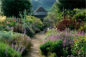 Parham. Sussex. Cool color borders in summer. Path with view through to dovecote