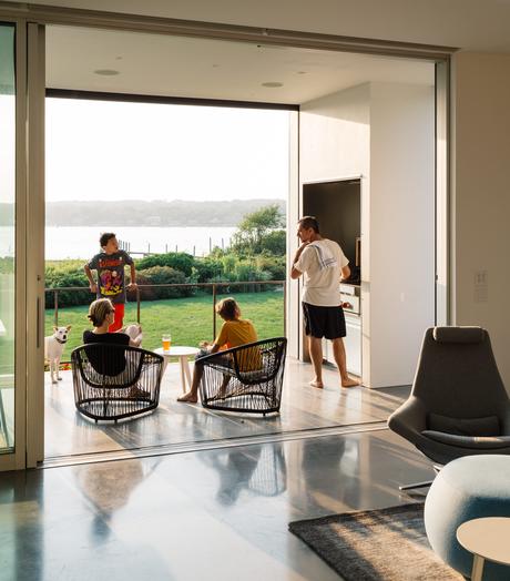 An Idyllic Rhode Island Summer Cottage Is the Perfect Escape for a New York Family Chairs by Zanotta, grill, and retractable insect screens from Phantom Screens on deck of Rhode Island family vacation home by Bernheimer Architecture.