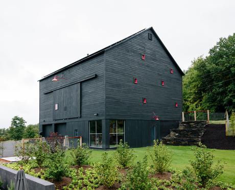 Red windows articulate the charred-wood facade of this Hudson Valley house. 