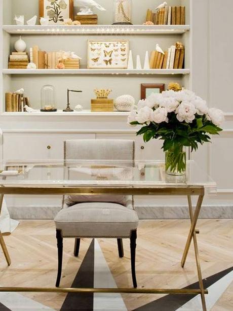 Glass and golden desk, gray chair, decorated shelves, white flowers: 