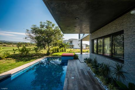 The upper level cantilevers over a wood deck and pool. 