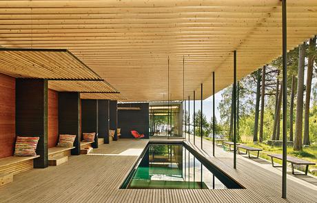 How a 1,000-Year-Old Technique Made This Pavilion Swedish guesthouse pavilion with pergola over the pool and george nelson benches