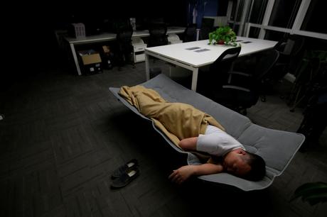 Ma Zhenguo, a systems engineer at RenRen Credit Management Co., sleeps on a camp bed at the office after finishing work in the early morning.