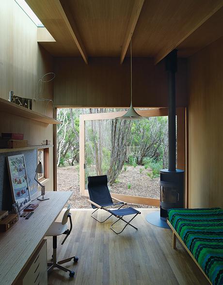Local Wood Covers This Getaway for Two Architects Australian studio with open glass door and wood-burning stove