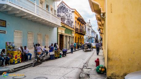 A horse-drawn buggy makes its way down a colorful street in Cartagena.