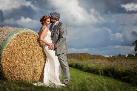 Rustic Wedding with Adam + Jaclyn groom kissing brides head against hay bails