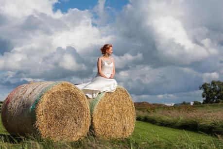Rustic Wedding with Adam + Jaclyn bride sitting on hay bails at a rustic wedding