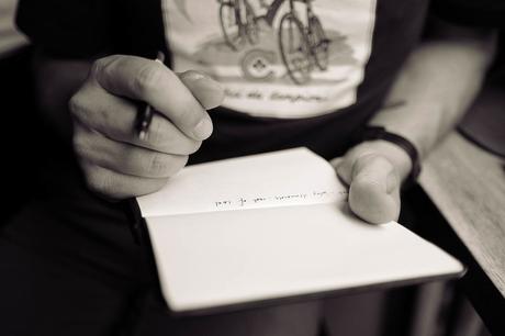 Man holding a notebook and writing some notes in black and white.