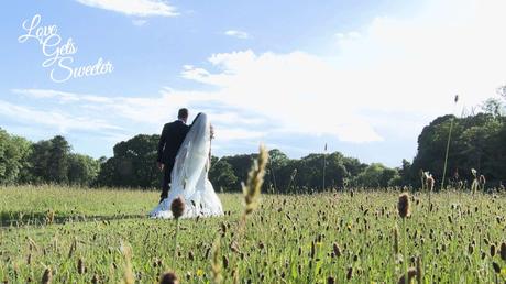 An Elegant and Stylish Lakes Wedding Video bride and groom take a stroll through the fields near the lake with her long cathedral length veil blowing in the wind