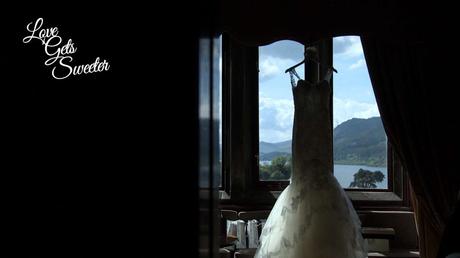 An Elegant and Stylish Lakes Wedding Video Pronovias fish tail lace wedding dress hanging in the window of Armathwaite Hall looking out to the lake district