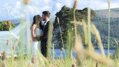 An Elegant and Stylish Lakes Wedding Video bride and groom having a kiss in the field by Armathwaite Hall in front of Bassenthwaite Lake for their wedding videographer