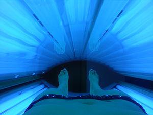 Woman uses a tanning bed.