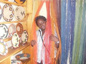Cissy poses amongst the multicoloured raffia - used to weave baskets Rubona Basket Weavers' Association
