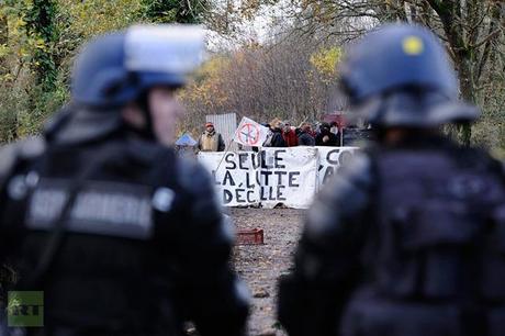 French anti-riot police officers stand in front of protesters holding a banner partially reading ′′Only the fight takes off′′ on November 24, 2012 in Notre-Dame-des-Landes as they seek to evict squatters from protected swampland where Prime Minister Jean-Marc Ayrault wants to build a new airport (AFP Photo / Jean-Sebastuen Evrard)