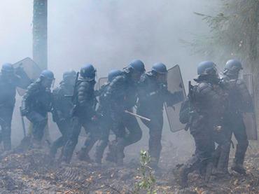 French anti-riot police officers walk through smoke from tear gas, on November 24, 2012 in Notre-Dame-des-Landes as they seek to evict squatters from protected swampland where Prime Minister Jean-Marc Ayrault wants to build a new airport (AFP Photo / Jean-Sebastuen Evrard)