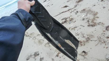 holding scuba diving flipper washed up on beach