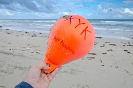 holding orange fishing buoy washed up on beach