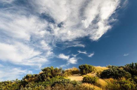 clouds and sun above sand dunes