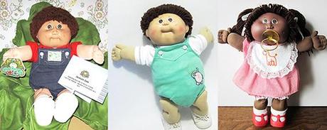 three Cabbage Patch Dolls from the early 1980s, one with cabbage leaf and certificate information card, a baby, and a black African American little girl wearing bib and sucking pacifier