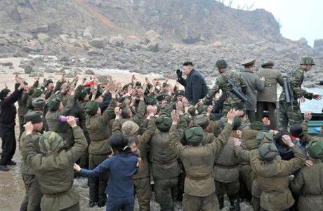 Kim Jong Un disembarks from a transport vessel, greeted by KPA service members and officers, and their family members, on Mu Islet in the West Sea.  Seen behind Kim Jong Un are two close protection escorts carrying automatic rifles and two other executives of KJU's bodyguard staff (Photo: Rodong Sinmun)