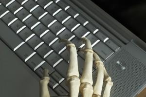 The boney hands of a skeleton type on a computer keyboard