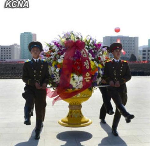 An honor guard delivers a floral basket sent by Kim Jong Un to a ceremony dedicating statues of his grandfather, late DPRK President and founder Kim Il Sung, and his father, late leader Kim Jong Il, at the headquarters of the Ministry of People's Security in Pyongyang on 14 April 2013 (Photo: KCNA)
