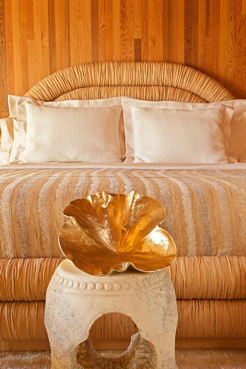 Kelly Wearstler beach house bedroom wood paneling round headboard gold clam shell
