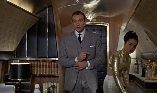 James Bond’s Iconic Goldfinger Suit Yeah, I'm sure this is the last place Bond wants to be. A gold-plated plane, a skimpy-dressed Asian stewardess, a well-stocked bar at his disposal, and a busty lesbian pilot. Give me a break.