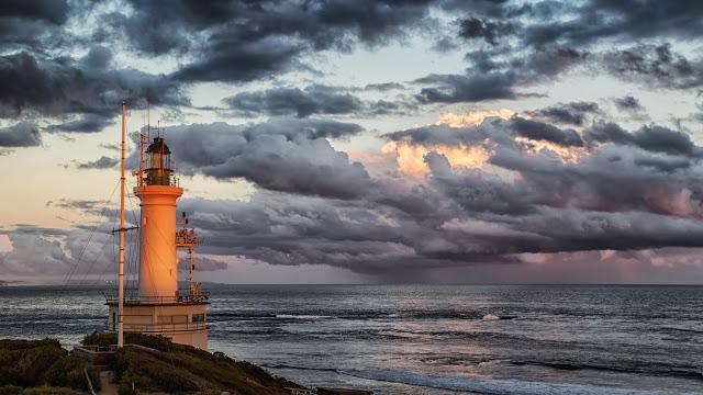 point lonsdale lighthouse with setting sun and rain clouds at sea