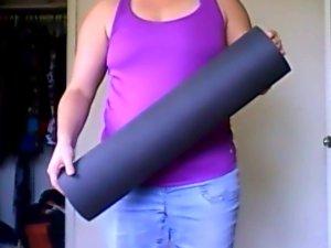 Person holding a black yoga mat.