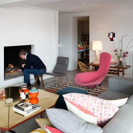 living room with concrete floors, white walls, gray Cappelini sofa, and pink Harry Bertoia wire chairs