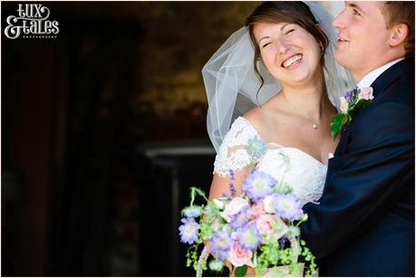 Relaxed natural pose of bride and groom at rustic wedding in old green barn in UK