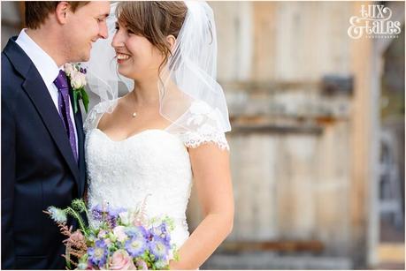 Bride and groom at Old Green Barn in UK smiling and holding wildflowers