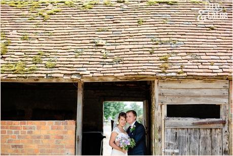 Natural wedding photograph of bride and groom in old green barn in Newdigate holding wildflower boutquet