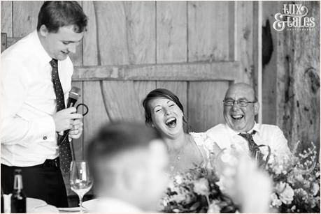 bride at UK barn wedding smilas and laughs during the speech in a natural relaxed moment