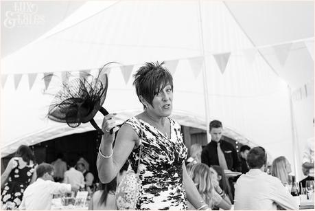 Mother of the groom holds up fascinator and makes funny face for camera at UK wedding