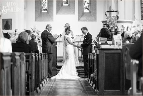 Bride smiles at the alter holding hands with groom in UK church 