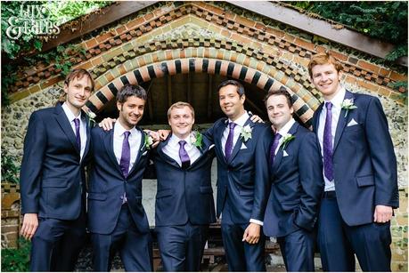 Groomsmen gather around groom in front of tudor detail building at UK wedding