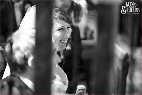 Reportage photograph of bride smiling in UK church taken in black and white