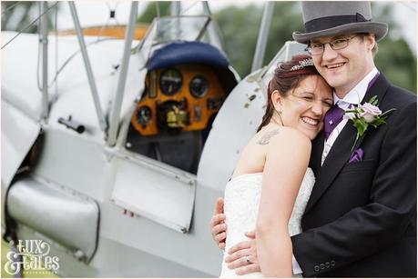 Bride and groom pose in front of a vintage aeroplane at Woburn Abbey Airshow 