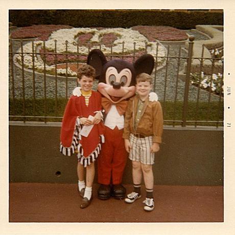 Two children standing with Mickey Mouse at Disney Land, 1971