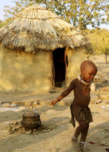Child dancing in front of a hut in the Kunene Region of Namibia